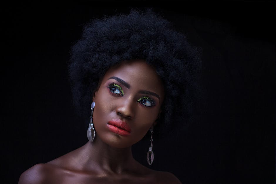 Close-up portrait of a beautiful black woman with striking makeup and elegant jewelry.