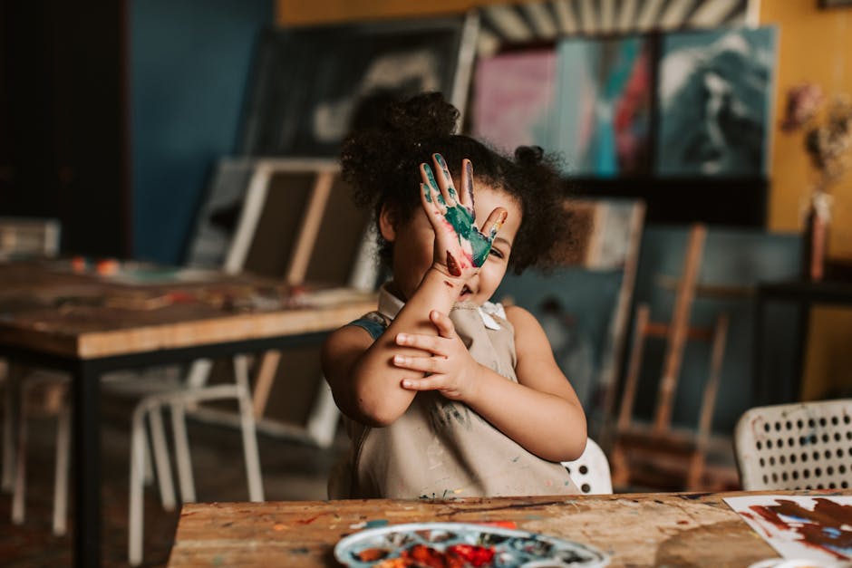 Joyful child showing painted hands in a vibrant art studio setting.