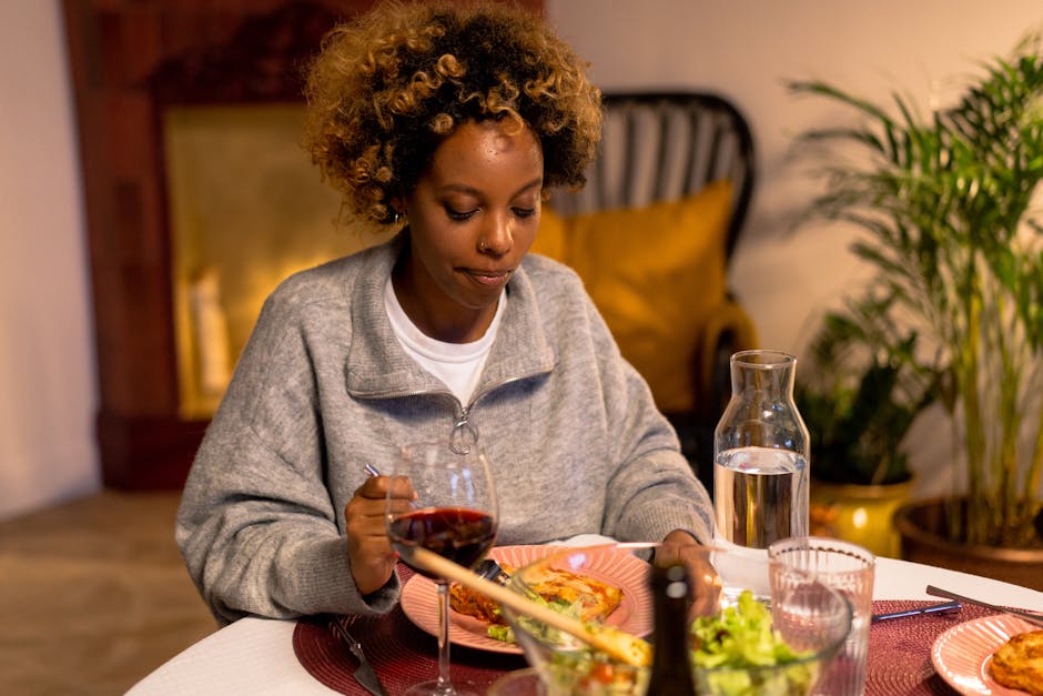 Young woman dining with wine and water indoors, in a cozy setting.
