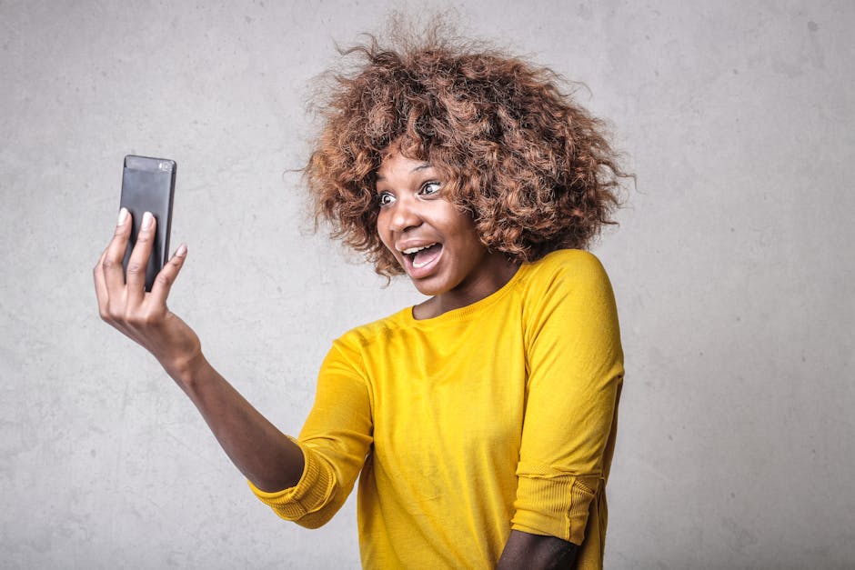 A cheerful woman with curly hair takes a selfie indoors, capturing happiness and technology.