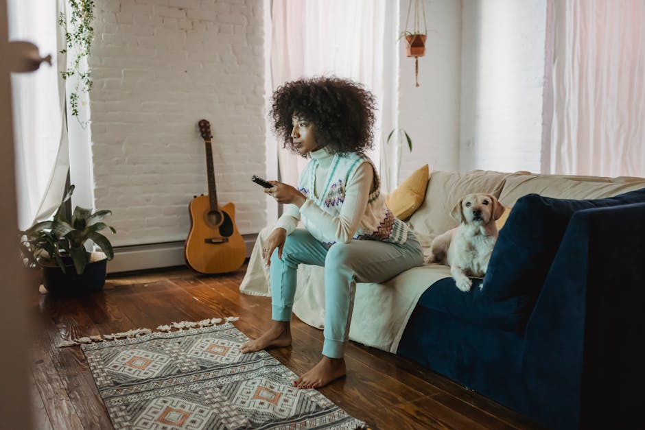 Young woman enjoys a cozy afternoon at home with her dog, watching TV and relaxing.
