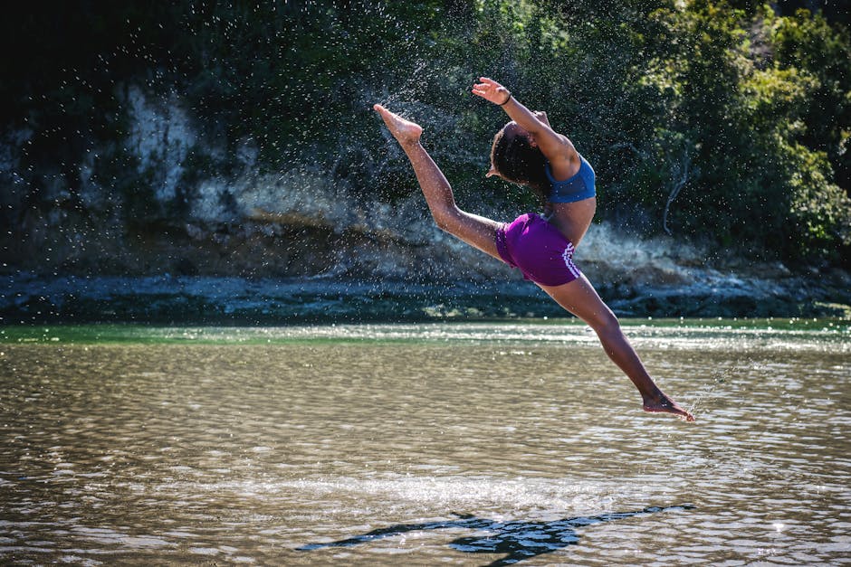 Young woman leaps in front of a river, showcasing flexibility and energy.