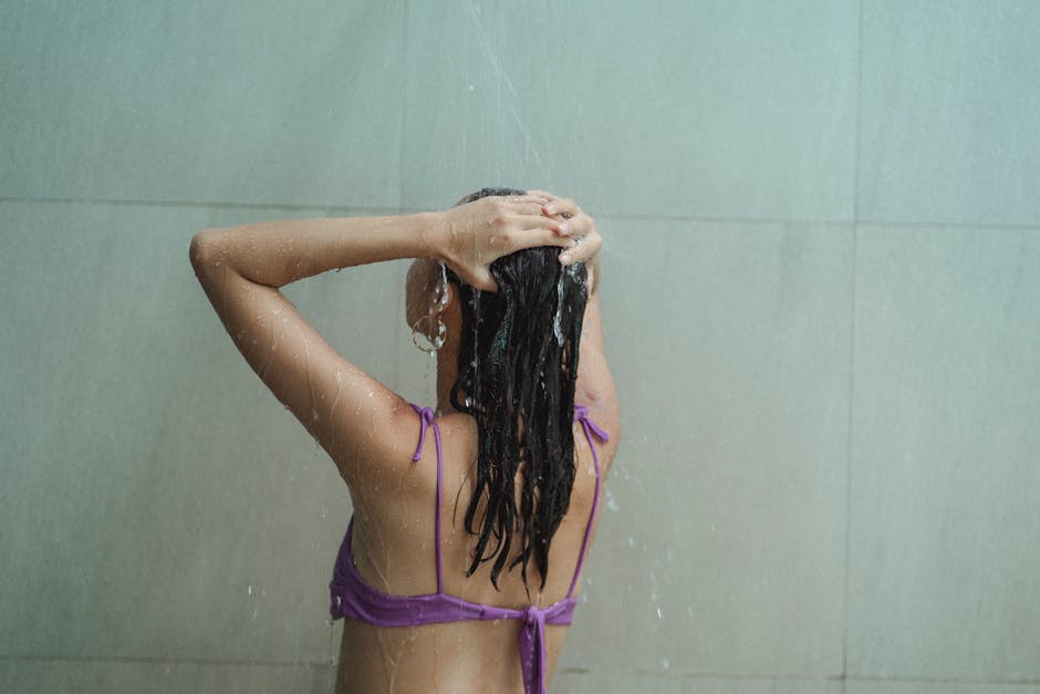 Woman enjoying a refreshing shower indoors, focusing on hygiene and relaxation.