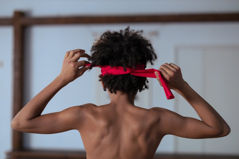 Back view of a boy tying a red headband indoors. Minimalist style.