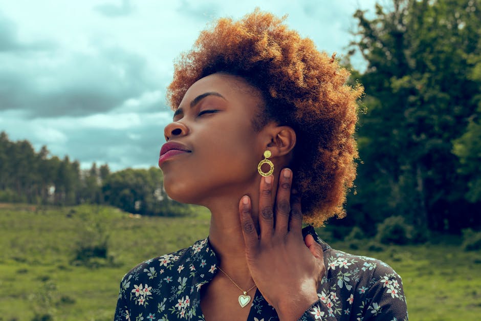 Stylish woman enjoying nature with a serene expression, showcasing fashion and beauty.