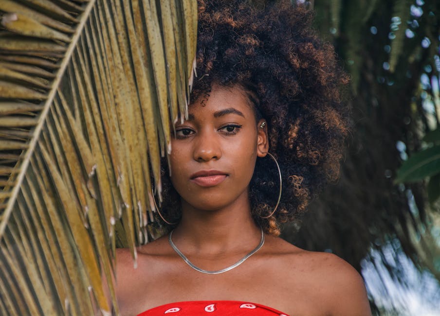 Portrait of a young woman with an afro hairstyle in a natural outdoor setting, with a carefree and stylish vibe.
