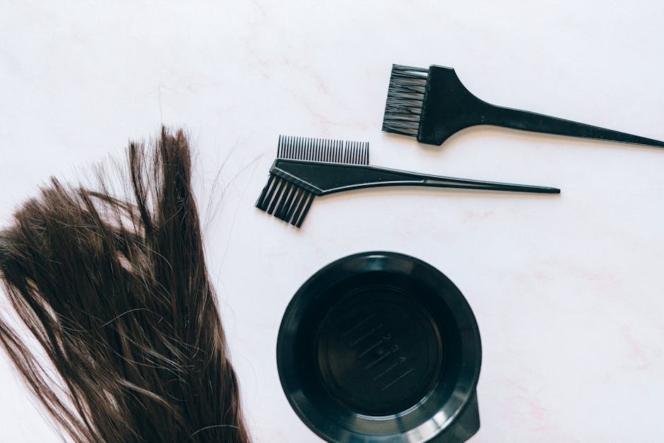 Top view of hair coloring tools and hair strands on a white background.