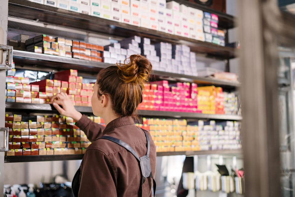 Hairdresser choosing hair dye from organized shelves in a beauty salon.
