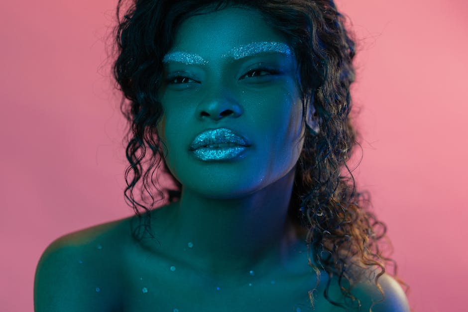 Elegant portrait of a woman in glitter makeup against a pink and blue backdrop.
