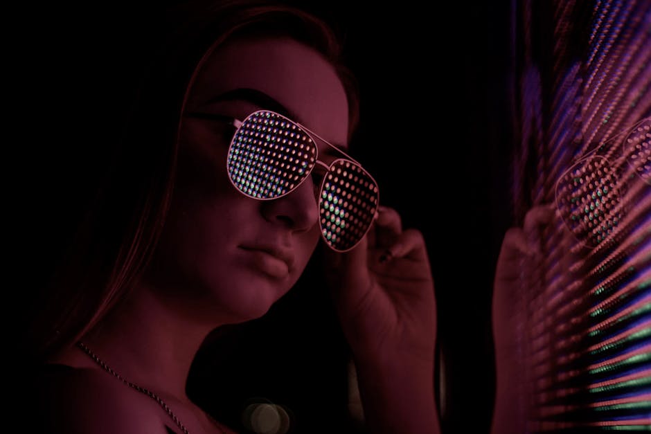 Stylish young woman posing indoors with vibrant reflective sunglasses, creating a modern and edgy look.